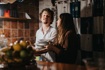 A cheerful pair enjoy washing dishes together, sharing laughter in a warmly lit kitchen setting.