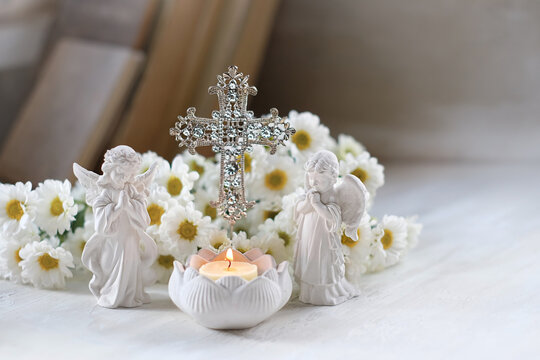 Beautiful angel figurines, burning candle, decorative openwork cross and flowers on table. symbol of Christianity religion, faith in God, prayer, memory. christian home altar.