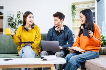 Three Asian young adult students sit in university living room, discussing their study abroad experiences, academic research, preparing thesis report, planning future global education opportunities.