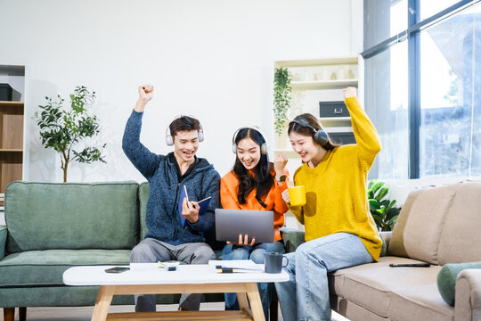 Three Asian young adult students sit in university living room, discussing their study abroad experiences, academic research, preparing thesis report, planning future global education opportunities.