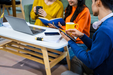 Three Asian young adult students sit in university living room, discussing their study abroad...