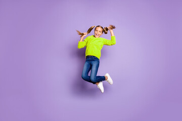 Fototapeta premium Full size photo of cheerful candid kid jump hold pigtails enjoy autumn holidays wear casual style clothes isolated over purple color background