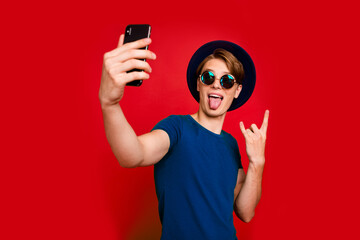 Portrait of funny funky guy hipster blogger take selfie show horns symbol enjoy rock concert...