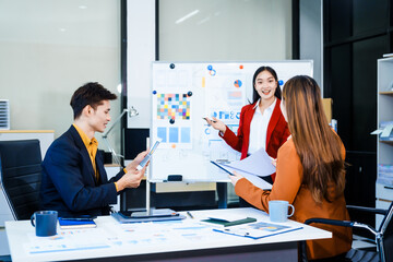Three Asian business professionals gather in boardroom for annual meeting, discussing strategic goals, future projections while proposing ideas, engaging in decision-making for corporate growth.
