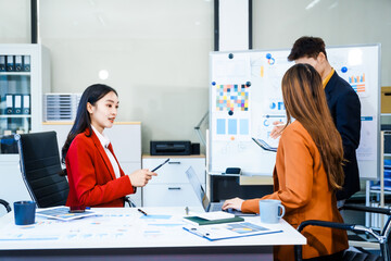 Three Asian business professionals gather in boardroom for annual meeting, discussing strategic goals, future projections while proposing ideas, engaging in decision-making for corporate growth.