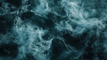 Dramatic aerial view of turbulent ocean waters with deep blues and frothy white waves.