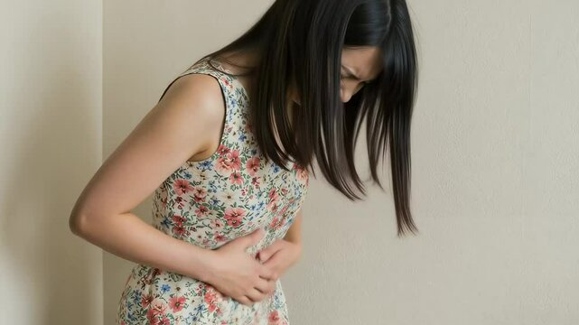部屋の隅で腹痛の痛みを堪えるワンピース姿の女性