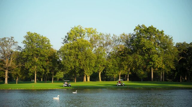 The golf course amidst water, natural landscape. The background with a lush green landscape with trees and people walking or relaxing Wide footage