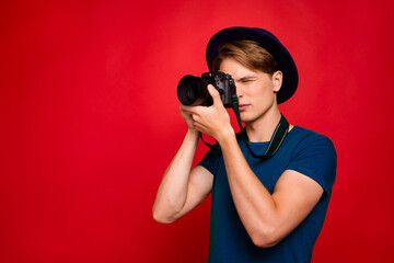 Obraz premium Profile side photo of concentrated guy have tour voyage abroad want shoot picture photo on his digital camera wear blue stylish trendy green t-shirt isolated over red color background