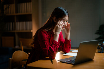 Exhausted female professional pressing fingertips against forehead, experiencing workplace stress...