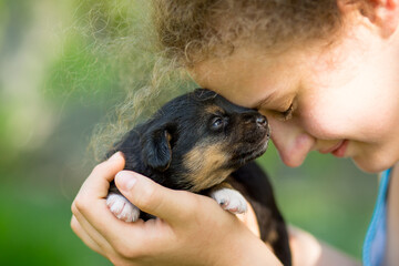 Curly blonde girl hugs newborn mongrel puppy