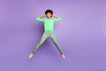 Full size photo of funky funny brunette curly hair mulatto girl jump make v-signs near her face wear casual style clothing sneakers isolated violet color background