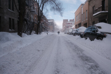 Two people walking in a street under a sown storm