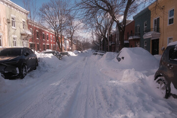 View on a snow-covered street with cars parked