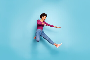 Full length photo of dark skin pretty wavy lady jumping high dancing modern youngster moves wear casual outfit isolated pastel blue color background