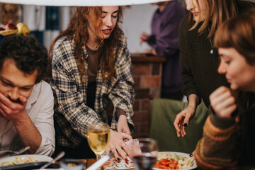 A warm gathering of friends around a meal, sharing food and moments together in a cozy indoor setting. People engaged in conversation and enjoying each other's company.