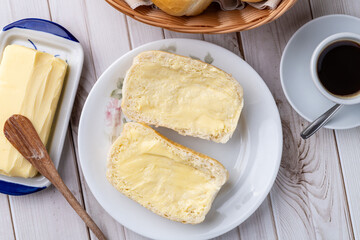 French bread or salt bread with butter and coffee over white wooden table