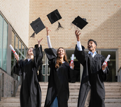 Group of cheerful multiethnic graduates throwing their graduation caps in the air after receiving their diplomas
