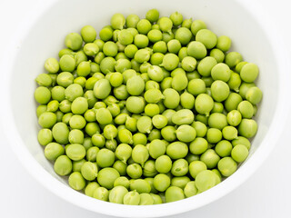 macro close-up of fresh organic green peas in a white bowl - food and agriculture concept