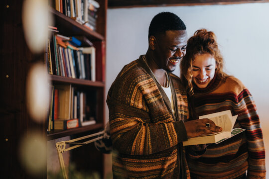 A joyful moment shared between two friends in a warm and inviting library interior, as they laugh and explore the pages of a book together.
