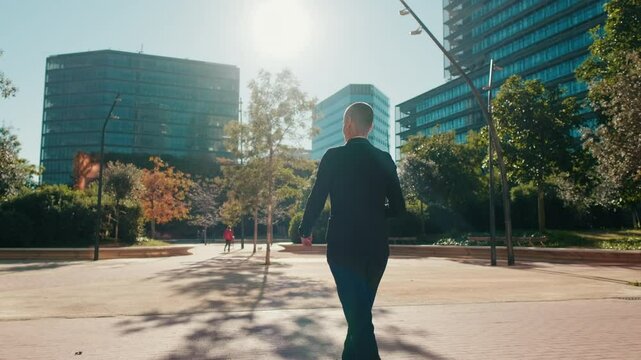 A businesswoman walks confidently through a modern city park, heading towards office buildings. She embodies ambition, success, and the urban lifestyle.