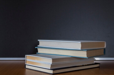 Pile of books on wooden table with dark background and copy space.