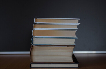 Pile of books on wooden table with dark background and copy space.