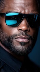 Obraz premium Black male police officer wearing sunglasses exudes seriousness against a white background