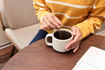 Woman having coffee break at wooden table in cafe, closeup
