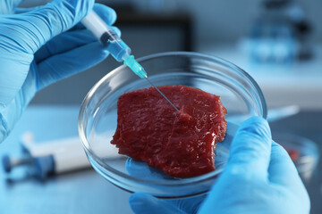 GMO concept. Scientist injecting something into piece of meat in laboratory, closeup