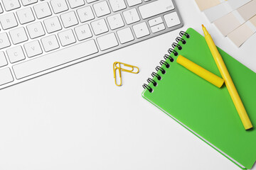 Designer's workplace with keyboard and stationery on light background, flat lay. Space for text