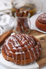 Tasty cinnamon roll with cream on white table, closeup