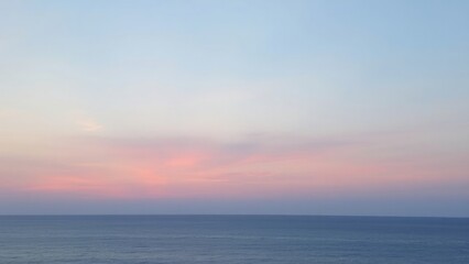Fototapeta premium Soft pastel sunset over the calm ocean, with gentle hues of pink, purple, and blue blending in the sky. The tranquil scene captures the serene beauty of nature.