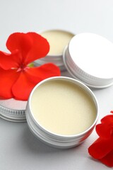 Lip balms and red flowers on white background, closeup