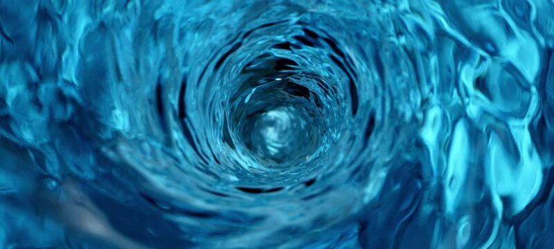Macro shot of blue water droplets swirl flowing inside of pure glass. Close-up shot with slow-motion camera