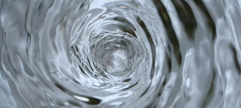 A directly above view of clear water rotating anticlockwise and creating a deep vortex