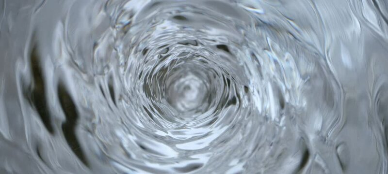 The water is pulling down and forced toward the drain hole in the center by gravity. shot on the high-speed camera