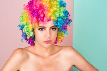 Naklejka premium Young woman in rainbow lgbtq flag wig looking positive and happy. Funny Girl smile. Young transgender woman in wig. Funny woman face. Portrait of attractive funny girl grimacing. Emotion girl.