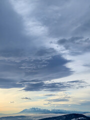 A breathtaking view of the Tatra Mountains under dramatic skies with shifting clouds illuminating the landscape at dusk. Perfect for nature lovers and travel enthusiasts.