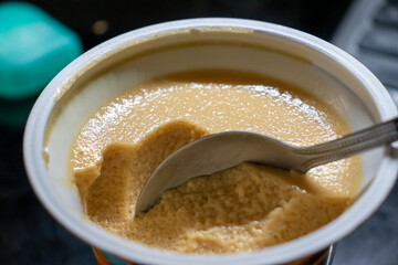 Creamy dessert in a bowl with a silver spoon ready to serve. Perfect for culinary concepts. Smooth texture and rich color evoke a sense of indulgence.