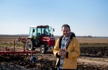 Farmer with tablet in front of tractor