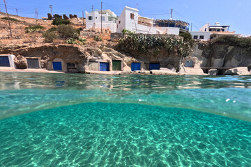 Underwater split photo of small cove of Rema famous for colourful boat houses called Sirmata, Kimolos island, Cyclades, Greece