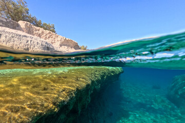 Fototapeta premium Underwater split photo of small cove of Goupa Kara famous for colourful boat houses called Sirmata, Kimolos island, Cyclades, Greece