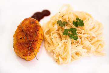 Meat cutlet with noodles and greens on a white plate