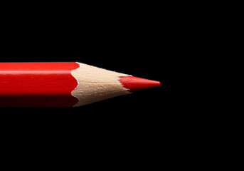 Obraz premium Close-up of a sharpened red pencil on a black background, symbolizing creativity, writing, and brainstorming ideas.
