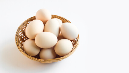 Organic eggs designed in a straw basket on white background with copy space 