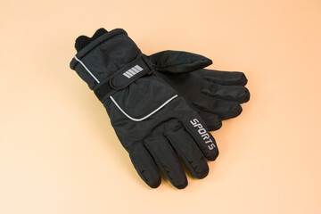 A pair of black winter sport gloves on yellow background