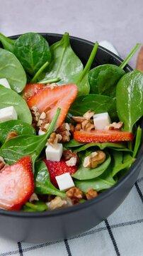 Vertical video, Healthy food concept, healthy lifestyle, fresh spinach salad with strawberries, aerial view