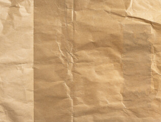 Old, wrinkled kraft paper texture in beige and brown tones. Creased and crumpled surface with a...