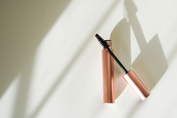 A rose gold mascara tube with its wand slightly angled rests on a clean, minimalist surface